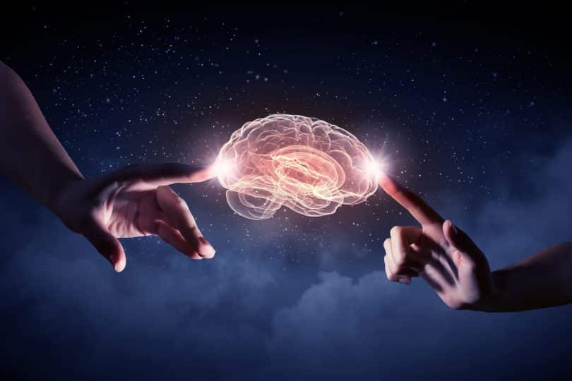 Ilustração de duas mãos tocando um cérebro brilhante em meio ao céu estrelado.