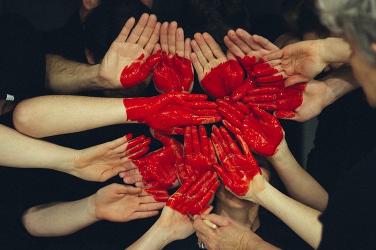 Mãos unidas formando coração com tinta vermelha