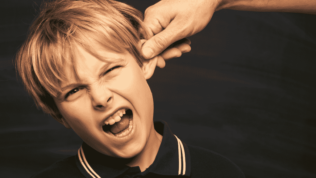 Criança sendo repreendida com puxão de orelha
