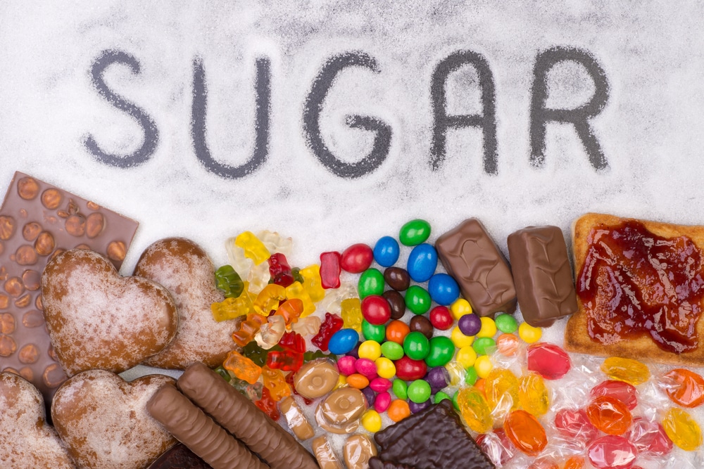 A palavra "sugar" escrita em cima do açúcar. Embaixo, há vários doces