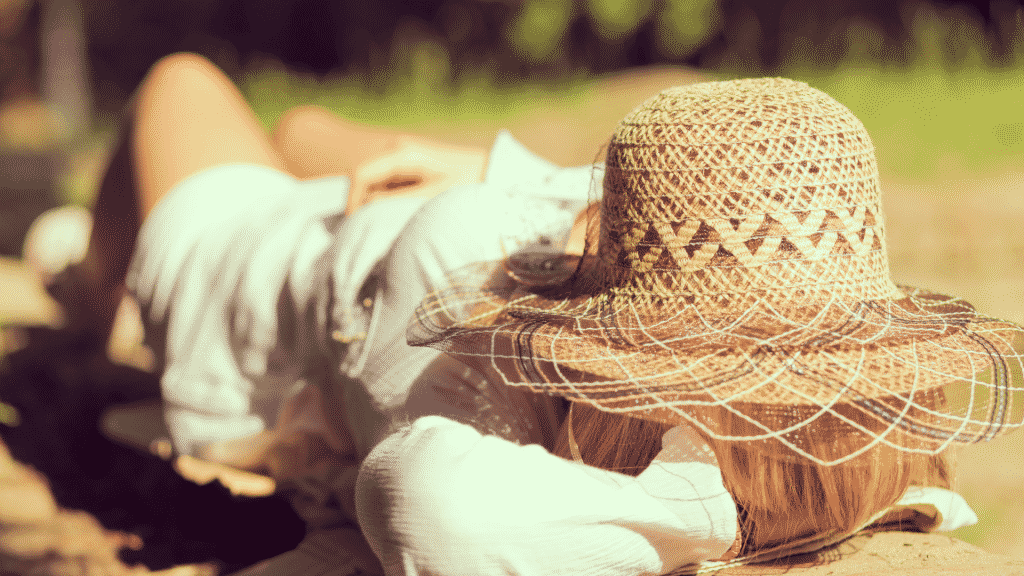 Mulher deitada no parque com chapéu de palha sobre o rosto