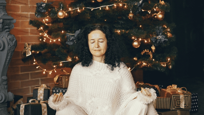 Mulher meditando embaixo da árvore de natal