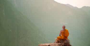 Monge budista meditando em uma montanha.