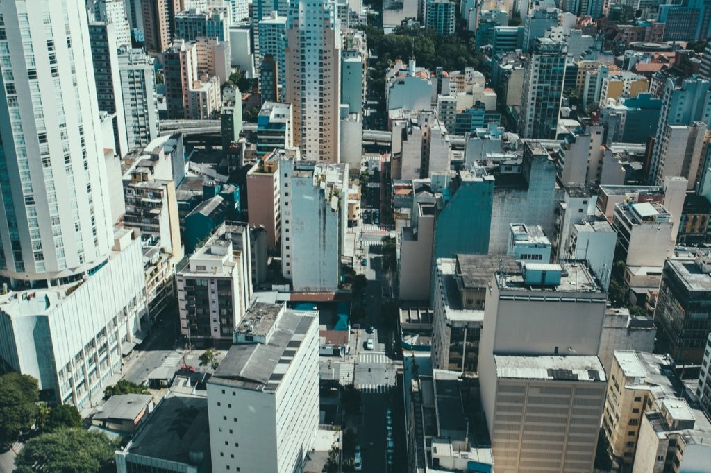 Imagem de uma cidade repleta de prédios vista de cima, durante o dia.