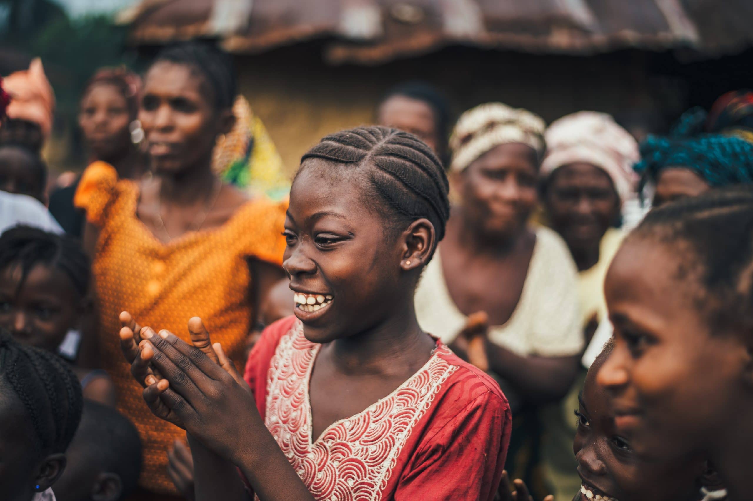 Mulher sorrindo com suas mãos unidas ao redor de outras pessoas