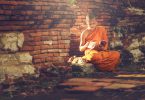 Menino budista sentado lendo um livro.
