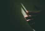 Imagem da mão de uma pessoa na parede e apenas um feixe de luz, iluminando