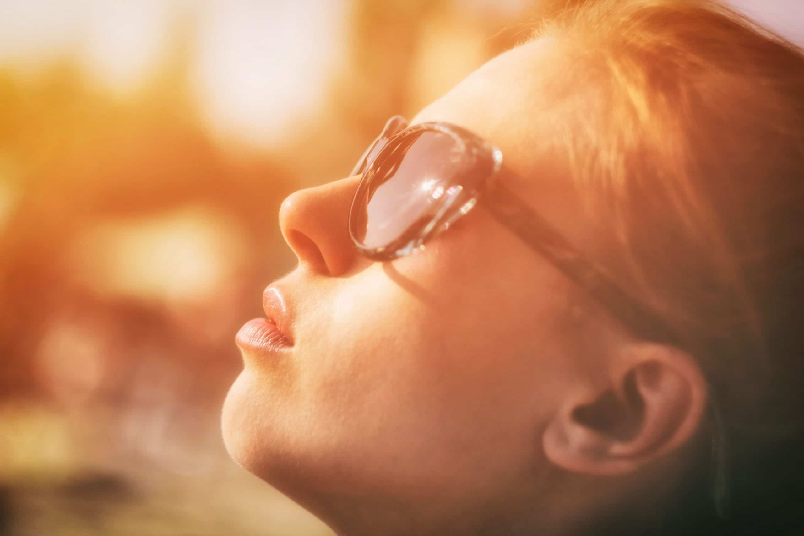 Mulher de perfil com óculos de sol com luz do sol refletindo