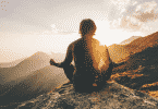 Homem meditando nas montanhas sob o pôr do sol