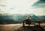 Mulher sentada em um banco observando a paisagem à sua frente.