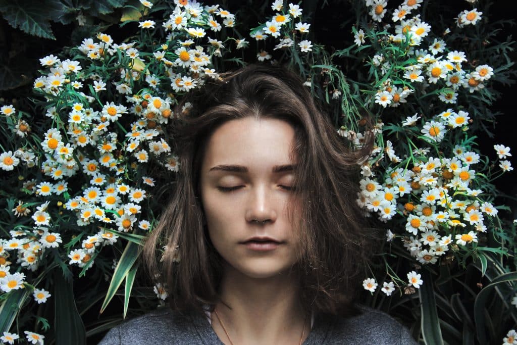 Mulher de olhos fechados com flores em volta de sua cabeça