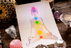 Ilustração em um papel de uma mulher com os sete chakras localizados em seu corpo. Ao lado, diversas pedras e cristais