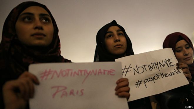 Mulheres jovens muçulmanas protestam contra ataques terroristas segurando placas om a hashtag "not in my name" (não em meu nome).