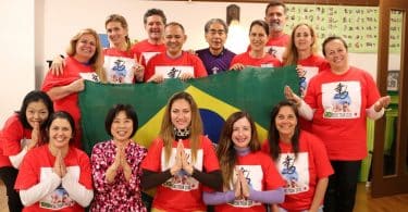 Grupo de pessoas com camisetas vermelhas, segurando uma bandeira do Brasil.