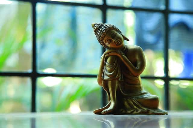 Imagem pequena de Buda apoiado em joelho