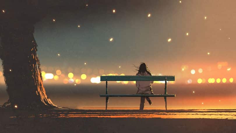 Mulher sentada num banco durante a noite.