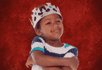 Criança usando coroa de rei com os braços cruzados