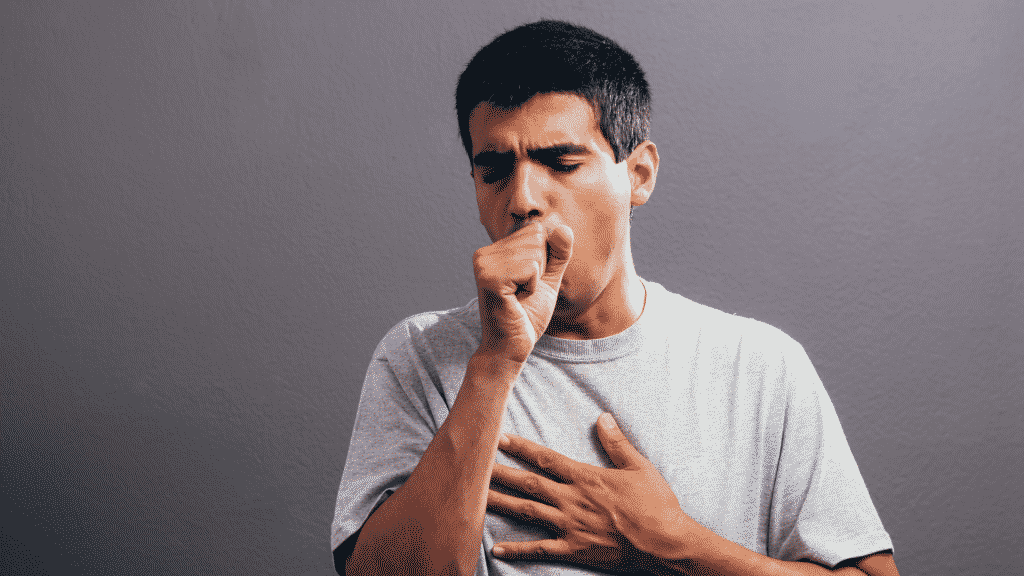 Imagem de um homem tossindo e com a mão no peito