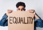 Homem marrom segurando placa escrito "equality".