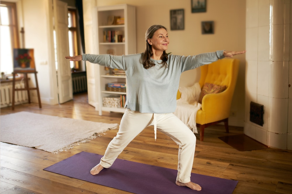 Mulher em uma posição de yoga em pé na sala de estar.