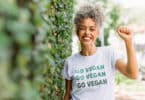 Uma mulher sorridente portando uma camiseta cuja inscrição é a frase "go vegan".