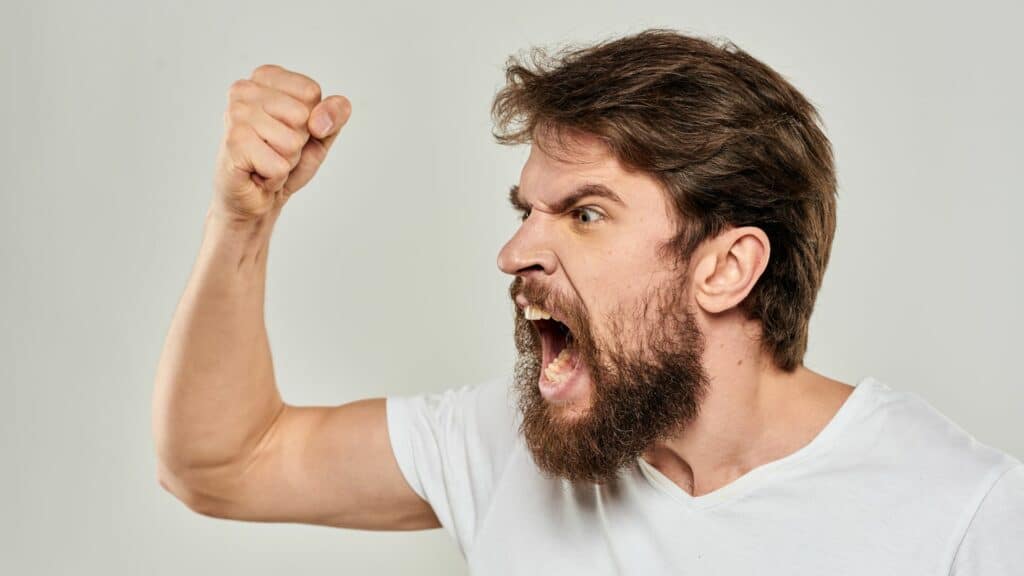 Imagem de um homem com o punho cerrado e feição de raiva, gritando
