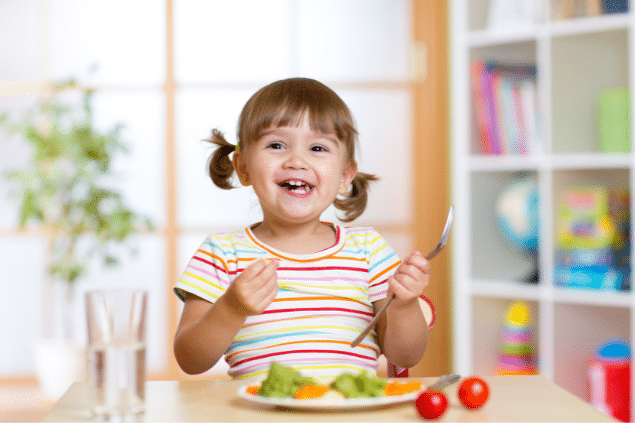 Menina comendo comidas saudáveis enquanto sorri