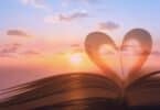 Imagem de um céu com o Sol ao fundo. Em destaque a imagem de um livro e um coração, representando a leitura, sabedoria e conhecimento