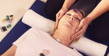 Terapia de Reiki com garota trabalhando como curandeira espiritual, organizando cristais e pedras preciosas em cliente do sexo feminino para tratamento