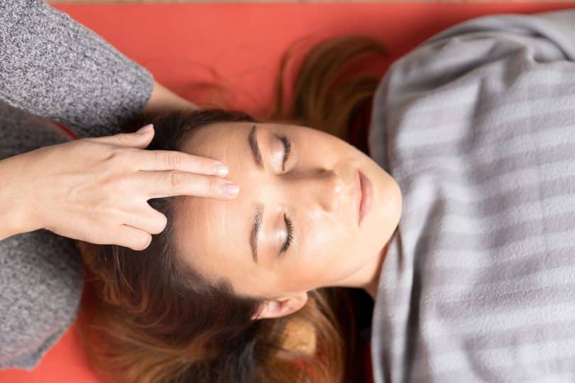 Mulher branca recebendo massagem na testa.