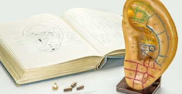 Mãos com luvas azuis aplicando adesivos na orelha de idosa branca.