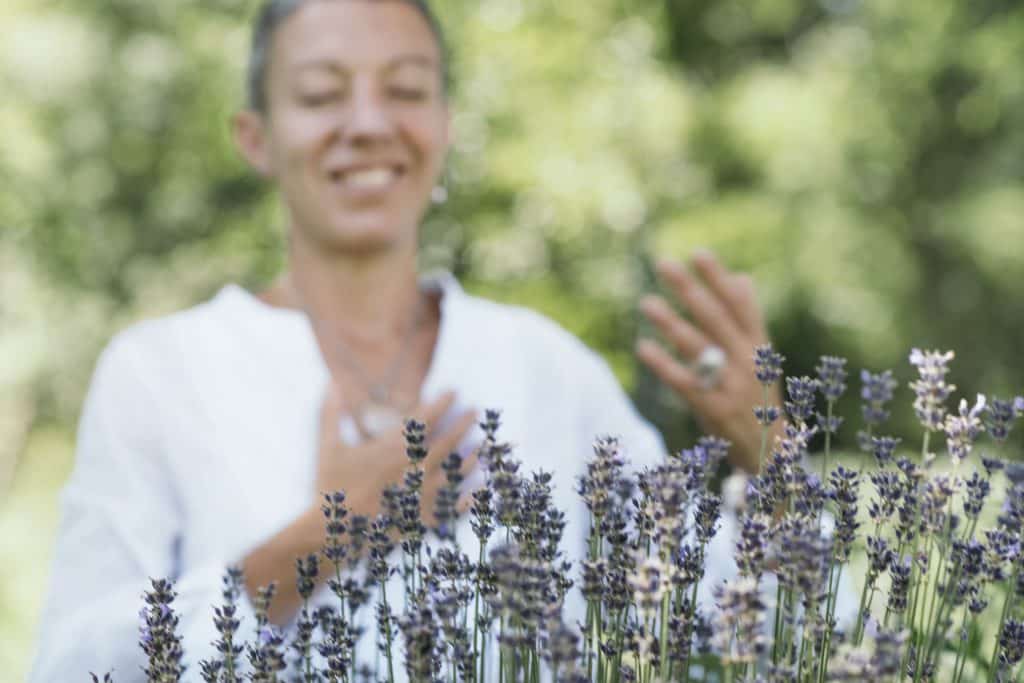 Mulher de olhos fechados sorrindo em frente a plantinhas