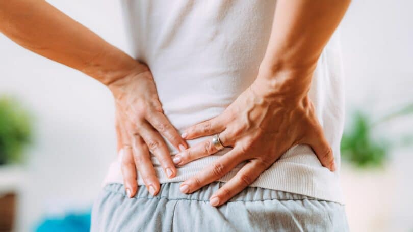 Mulher com dor no ciático com as mãos na região