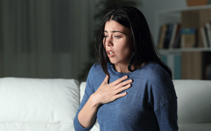 Mulher tendo um ataque de ansiedade com a mão no peito.