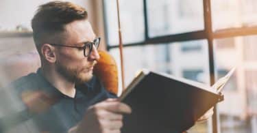 Homem branco lendo livro.