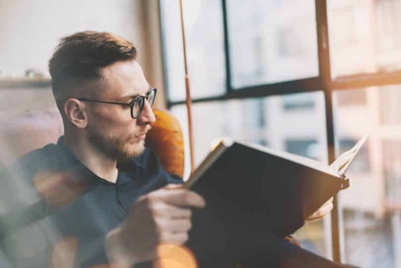 Homem branco lendo livro.