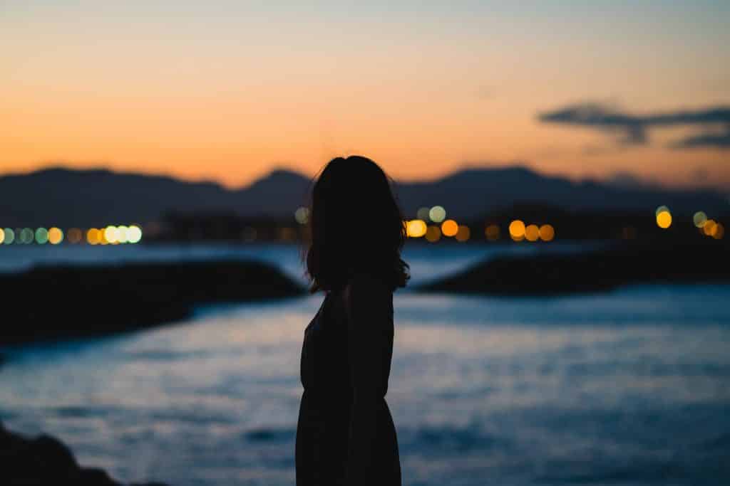 Mulher em frente a um lago olhando pra a cidade