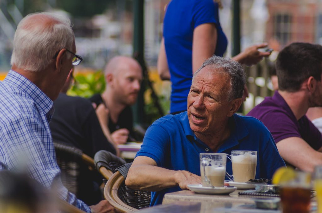 Dois homens sentados em uma cafeteria conversando.