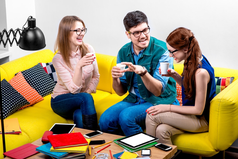 Três pessoas conversando enquanto tomam café.