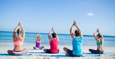 Pessoas fazendo meditação em grupo na praia