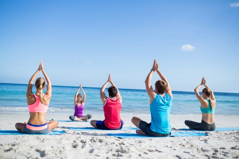 Pessoas fazendo meditação em grupo na praia