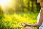 Braço de mulher meditando com fundo verde e sol refletindo