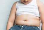 Recorte de um menino com a barriga de fora em fundo cinza.