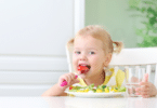 Menina comendo um prato cheio de legumes