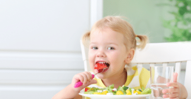 Menina comendo um prato cheio de legumes