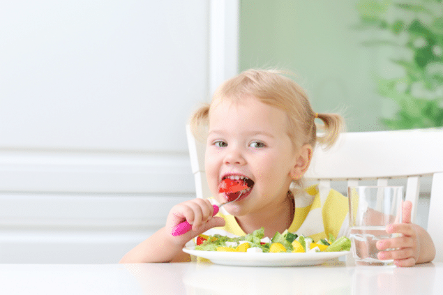 Menina comendo um prato cheio de legumes