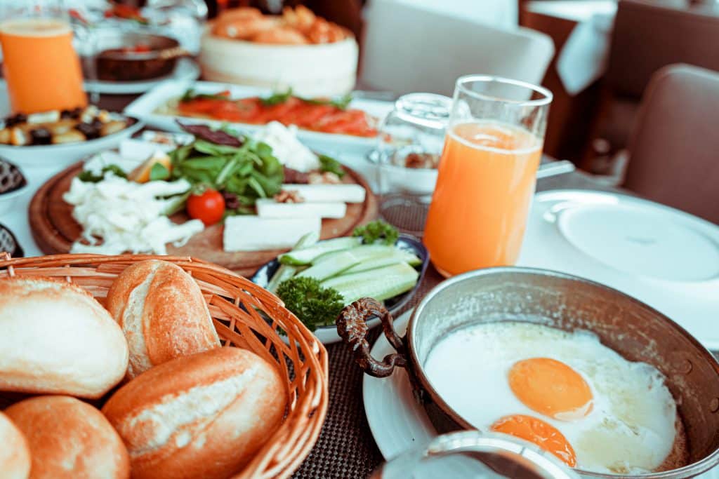 Mesa com ovos fritos, suco, pães