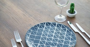 Prato na mesa com garfo e faca ao lado junto com uma taça de vinho