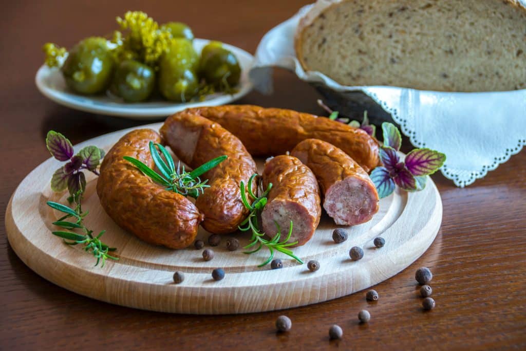 Mesa com linguiça e atrás um pedaço de pão