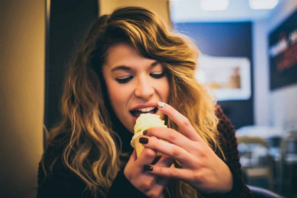 Mulher comendo um cupcake.